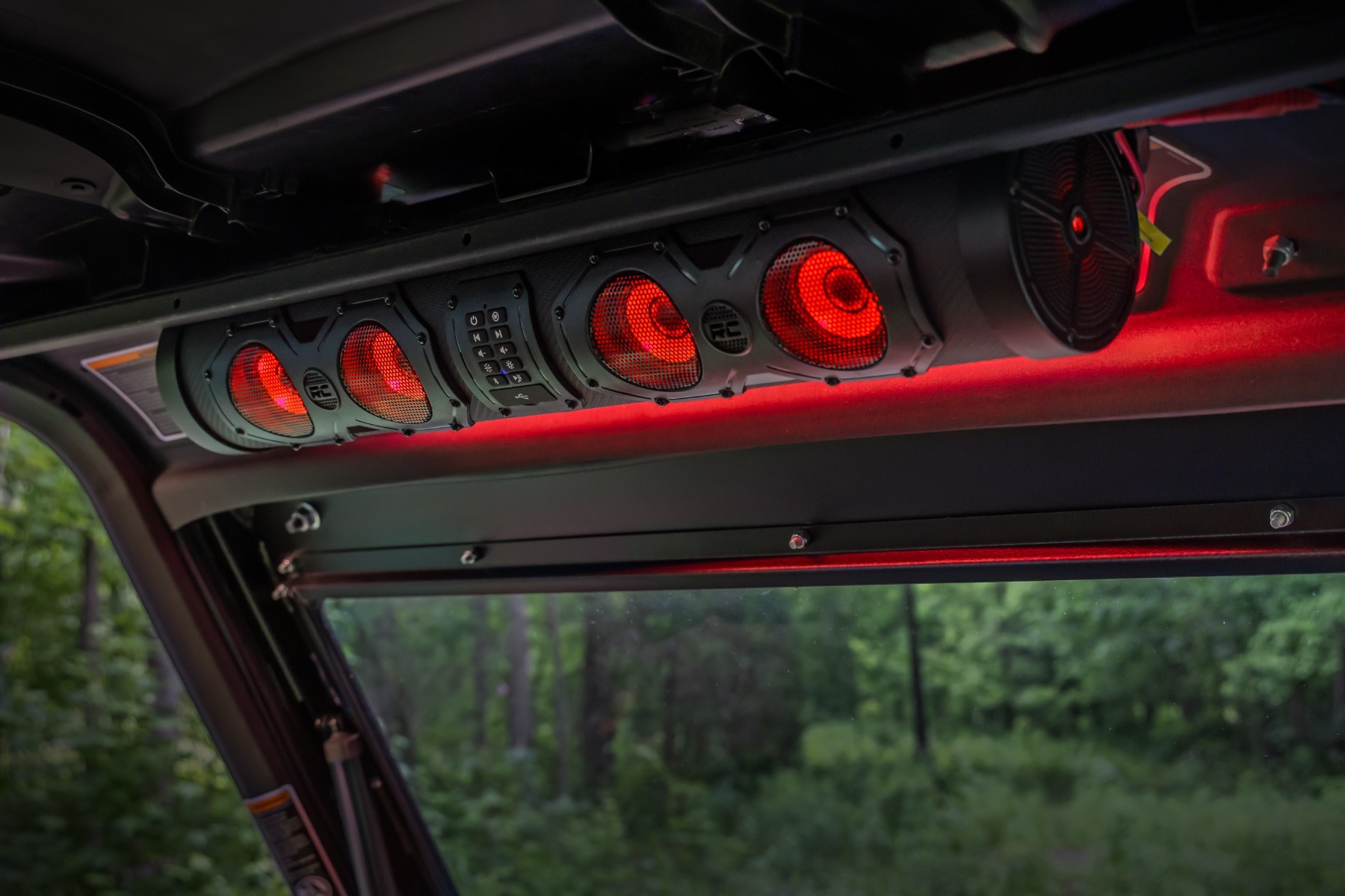 99515_A Rough Country 8 Speaker IP66 Waterproof Bluetooth LED Soundbar A cylindrical, rugged off-road 99515_A Rough Country mounted horizontally beneath the dark roof frame of a vehicle interior.